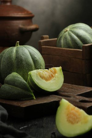 Photo for Green and black melon fruit on wooden background - Royalty Free Image
