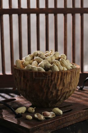 Photo for A vertical shot of a bowl of nuts and peanuts on the table - Royalty Free Image
