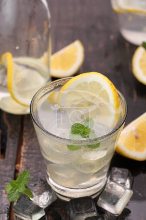 Foto de Vaso de limonada con limón y cubitos de hielo sobre mesa de madera - Imagen libre de derechos
