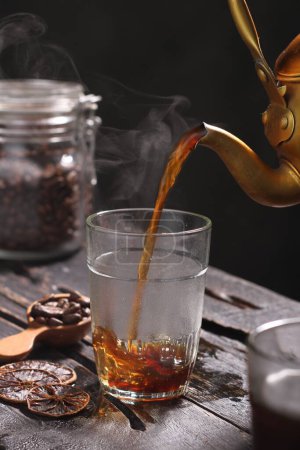 Foto de Granos de café en un frasco de vidrio y una taza de café en una mesa de madera negra. - Imagen libre de derechos