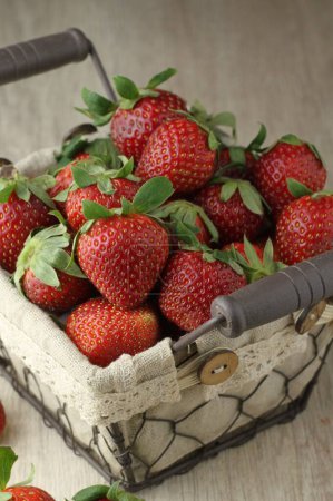 Photo for Fresh strawberries in a wicker basket on a wooden table - Royalty Free Image