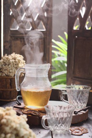 Téléchargez les photos : Thé chaud dans une tasse et un bocal en verre sur la table - en image libre de droit