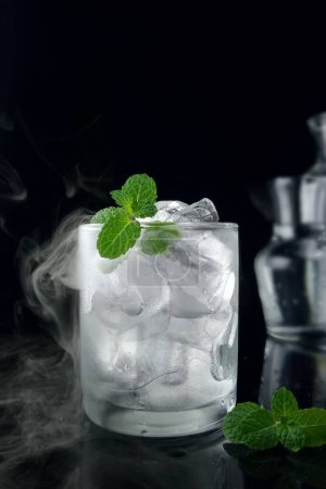 Foto de Vaso de menta fresca con cubitos de hielo y cubitos de hielo sobre fondo negro - Imagen libre de derechos