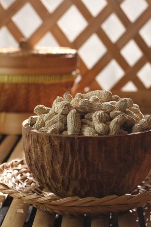 Photo for Bowl of peanuts with walnuts and wicker wicker on a wooden table. - Royalty Free Image