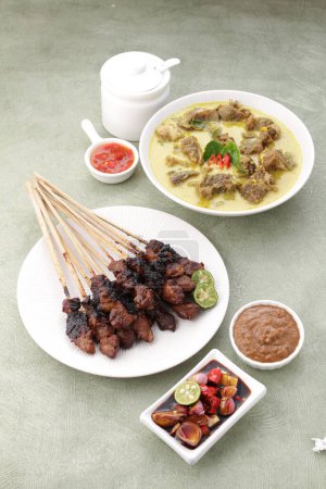 Foto de Comida indonesia, sopa de cabra servida con jugo de lima, tomates en rodajas, cebolletas en rodajas y salsa de chile picante - Imagen libre de derechos