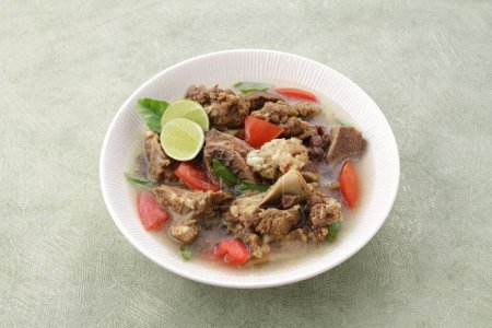 Foto de Comida indonesia, sopa de cabra servida con jugo de lima, tomates en rodajas, cebolletas en rodajas y salsa de chile picante - Imagen libre de derechos