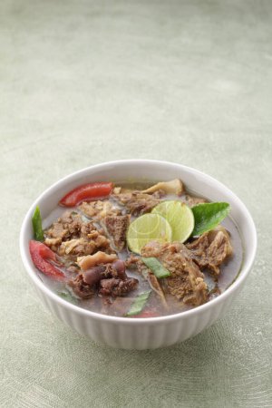 Photo for Indonesian food, goat soup served with lime juice, sliced tomatoes, sliced spring onions and hot chili sauce - Royalty Free Image