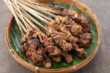 Téléchargez les photos : Satay de chèvre servi avec sauce aux arachides ou sauce soja aux échalotes tranchées, concombre et poivre de Cayenne - en image libre de droit