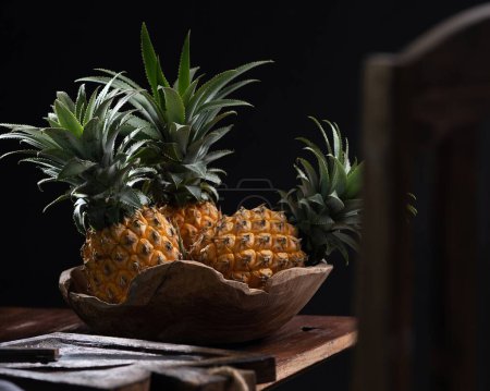Photo for Pineapple in the bowl on a black wooden table - Royalty Free Image