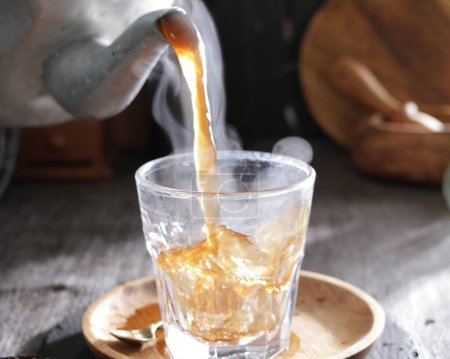 Foto de Verter té caliente con una taza de té sobre fondo de madera - Imagen libre de derechos