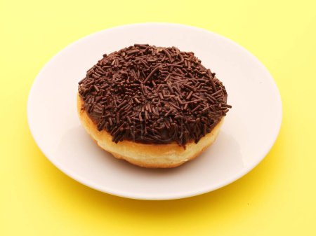 Photo for Chocolate donut with a plate on a yellow background. - Royalty Free Image