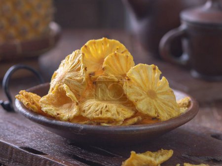 Photo for A bowl of pineapple chips on a wooden table - Royalty Free Image