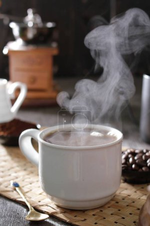 Téléchargez les photos : Une tasse de chocolat chaud avec une cuillère et une cuillère reposer sur un napperon - en image libre de droit