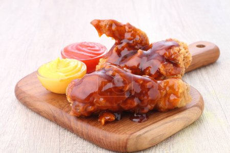 Photo for A wooden cutting board topped with chicken wings covered in sauce - Royalty Free Image