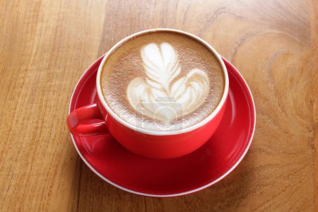 Foto de Una taza de café rojo con un diseño de hoja en ella - Imagen libre de derechos