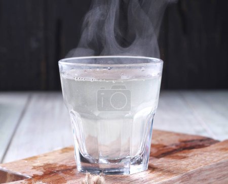 Téléchargez les photos : Un verre d'eau avec de la vapeur qui en sort - en image libre de droit