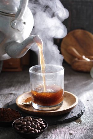 Téléchargez les photos : Une théière versant le thé dans une tasse - en image libre de droit