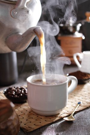 Photo for A cup of coffee being poured into a teapot - Royalty Free Image