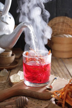 Téléchargez les photos : Un verre de liquide rouge avec une bouilloire à thé en arrière-plan - en image libre de droit