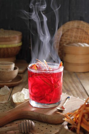 Téléchargez les photos : Un verre de liquide rouge avec une fumée qui s'échappe - en image libre de droit