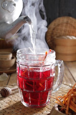Téléchargez les photos : Une théière versant du thé dans une tasse en verre - en image libre de droit