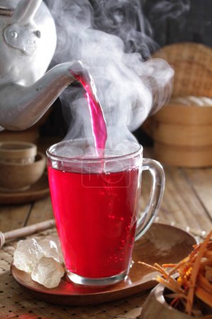 Téléchargez les photos : Une théière versant un liquide rouge dans une tasse - en image libre de droit