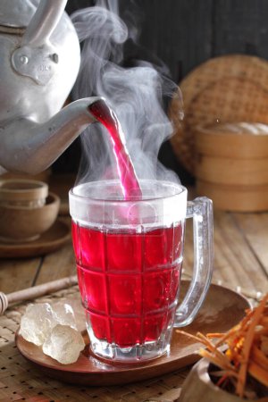 Téléchargez les photos : Une théière versant un liquide rouge dans un verre - en image libre de droit