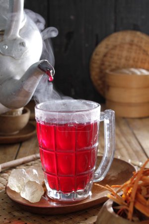 Téléchargez les photos : Une théière versant le thé dans une tasse en verre - en image libre de droit