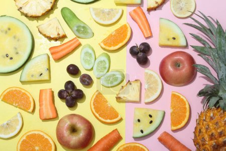 Téléchargez les photos : Une variété de fruits et légumes disposés sur un fond rose et jaune - en image libre de droit