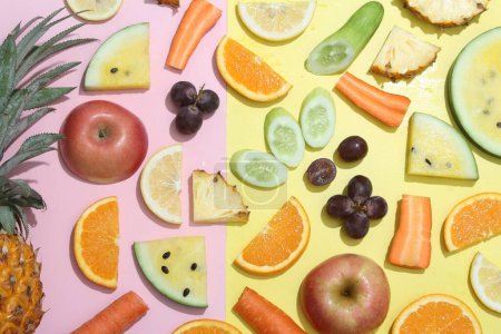 Photo for A variety of fruits and vegetables arranged on a pink and yellow background - Royalty Free Image