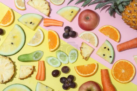Photo for A variety of fruits and vegetables arranged on a pink and yellow background - Royalty Free Image
