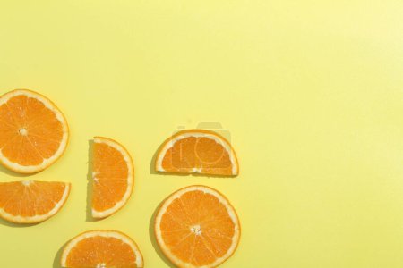 Téléchargez les photos : Un groupe de tranches d'orange sur une surface jaune - en image libre de droit