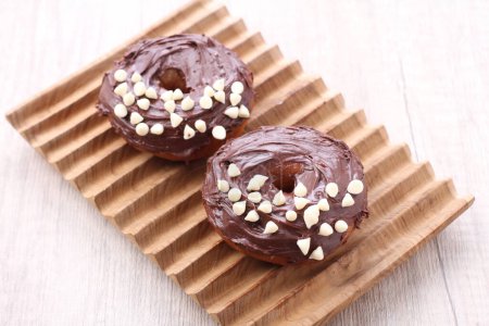 Photo for Two chocolate donuts with white sprinkles on a wooden tray - Royalty Free Image