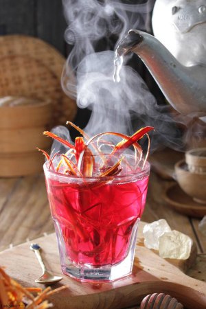 Foto de Un vaso de líquido rojo con una tetera en el fondo - Imagen libre de derechos