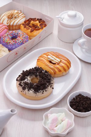 Foto de Deliciosas rosquillas de colores con café y té en la mesa - Imagen libre de derechos