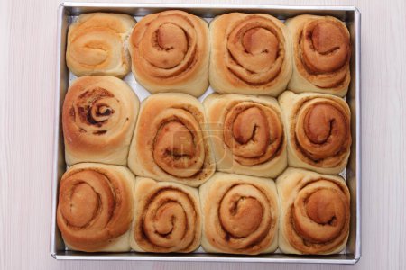 Téléchargez les photos : Petits pains à la cannelle sur une plaque à pâtisserie. cuisson au four. cuisson au four. vue de dessus. - en image libre de droit