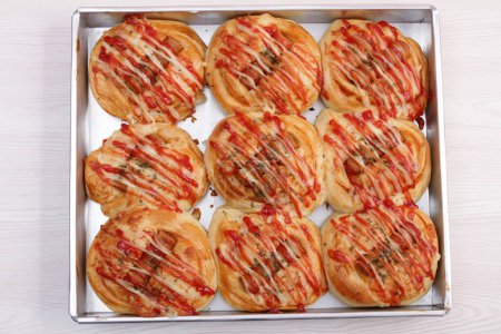 Téléchargez les photos : Rouleaux de saucisses maison avec sauce tomate sur un plateau blanc sur fond blanc. - en image libre de droit