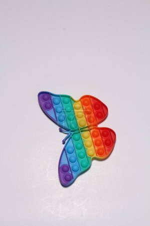 Téléchargez les photos : Jouet coloré - arc-en-ciel en forme - papillon sur fond blanc - en image libre de droit