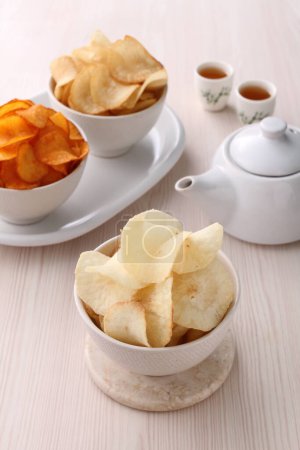 Téléchargez les photos : Croustilles de pommes de terre avec sauce aigre sur une assiette blanche et une tasse de thé - en image libre de droit