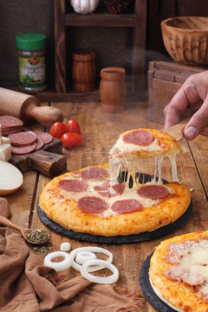 Foto de Pizza casera con queso y especias en mesa de madera - Imagen libre de derechos