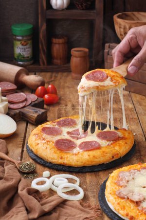 Téléchargez les photos : Pizza aux saucisses, fromage, tomates et champignons - en image libre de droit