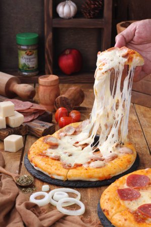 Téléchargez les photos : Pizza avec fromage, tomates, olives, épices et fromage sur une planche en bois. - en image libre de droit