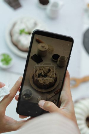 Photo for Woman holding smartphone with tasty dessert, closeup - Royalty Free Image