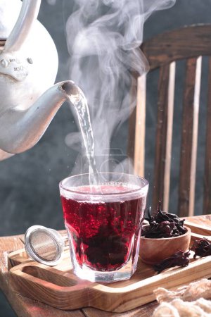Photo for Cup of hot tea with a spoon and a teapot on the wooden table. - Royalty Free Image