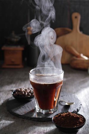 Foto de Café negro con humo y canela sobre mesa de madera - Imagen libre de derechos