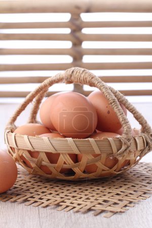 Téléchargez les photos : Panier en osier avec des œufs bio frais sur la table. espace pour le texte - en image libre de droit