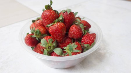 Foto de Fresas frescas en un tazón de plástico transparente. Delicioso, dulce, jugoso y maduro fondo de bayas con espacio de copia para el texto - Imagen libre de derechos
