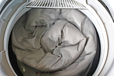 Foto de Roll up the duvet and put it in the washing machine.For the presentation of the washing machine. - Imagen libre de derechos