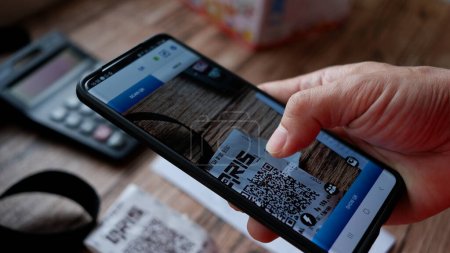 Téléchargez les photos : QRIS code scan from smartphone for cashless payment. Payment concept. Jakarta, 8 April 2022. - en image libre de droit