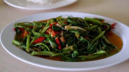 Foto de Stir-fried water spinach with Tauco on a white plate with rice. Tumis kangkung Tauco. Indonesia Food. - Imagen libre de derechos